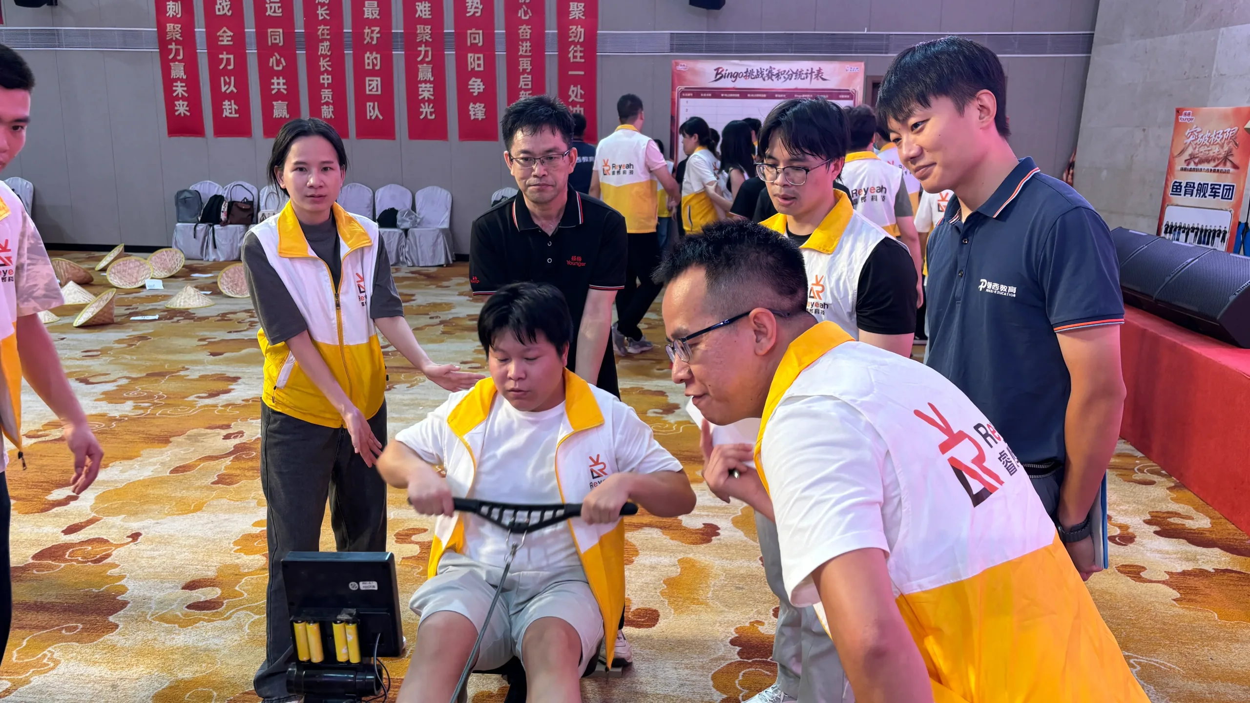 Participants supporting a teammate during a collaborative challenge activity in the hotel ballroom