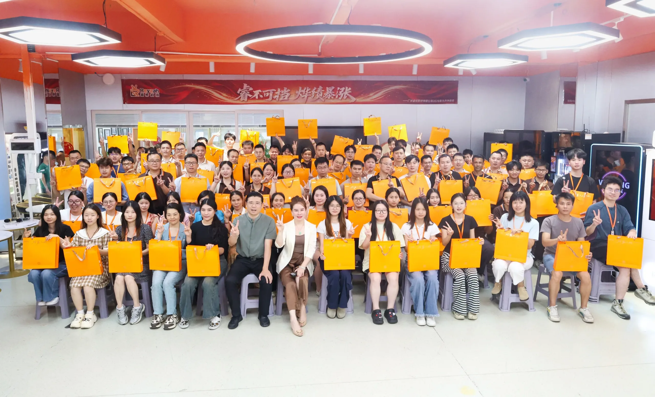 Reyeah employees from marketing, sales, production and R&D holding Mid-Autumn gift bags in the showroom beside modern vending machines