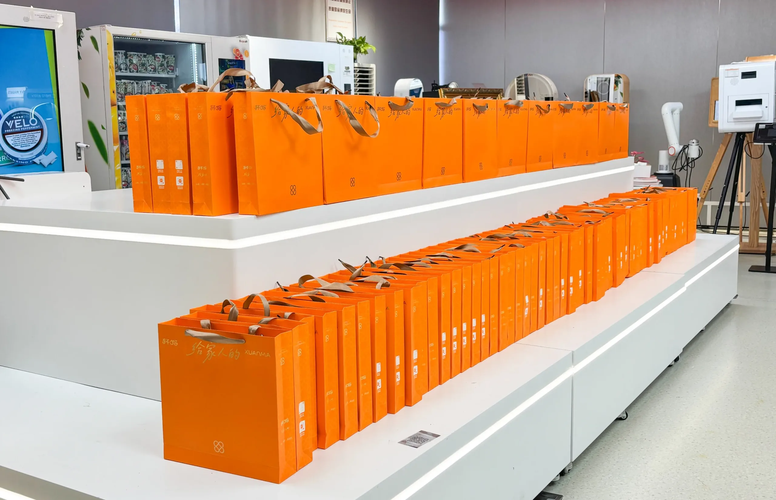 Orange Mid-Autumn gift bags with egg-yolk pastries arranged in the Reyeah showroom before employee distribution for the modern vending machines team